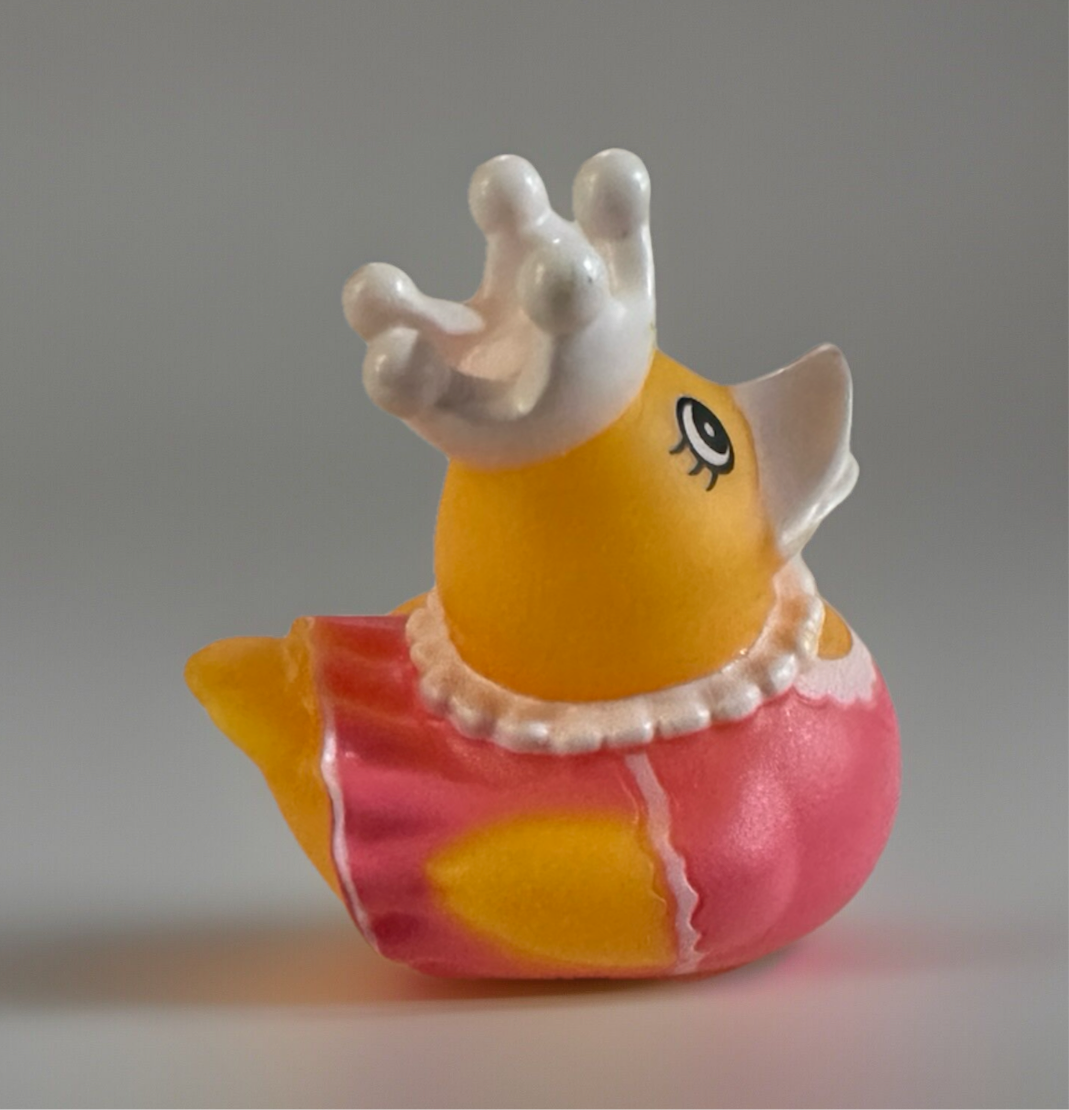 2 inch princess duck toy with yellow body, pink dress, white pearl necklace, and silver crown