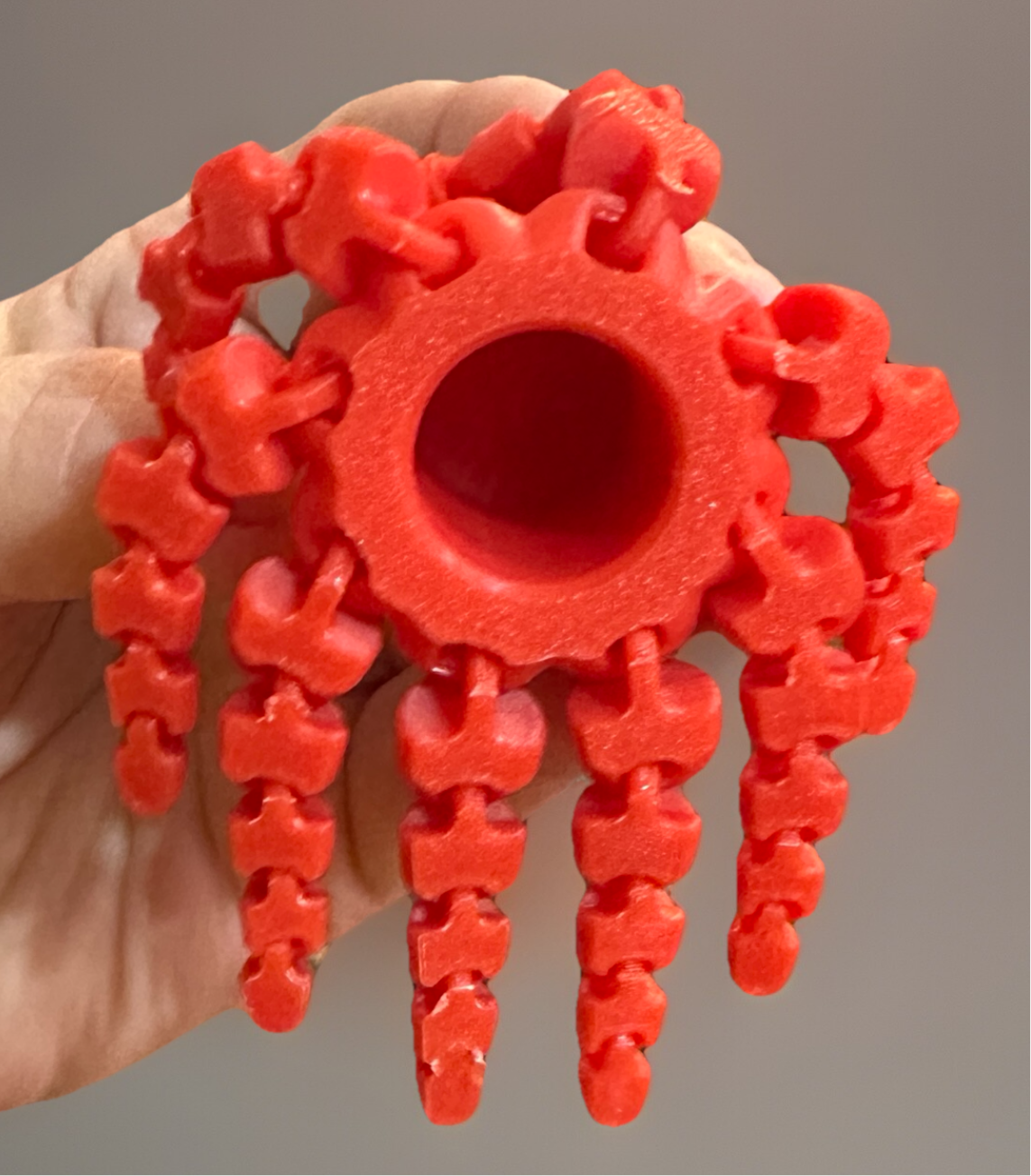 Red 3D articulated fidget octopus toy held in hand showing flexible tentacles from Reeds Rubber Ducks and Sensory Shop