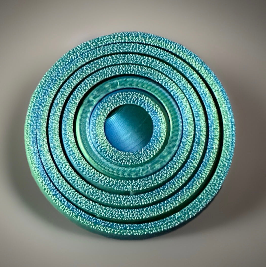 Close-up of metallic blue 3D gyro fidget spinner with textured concentric rings