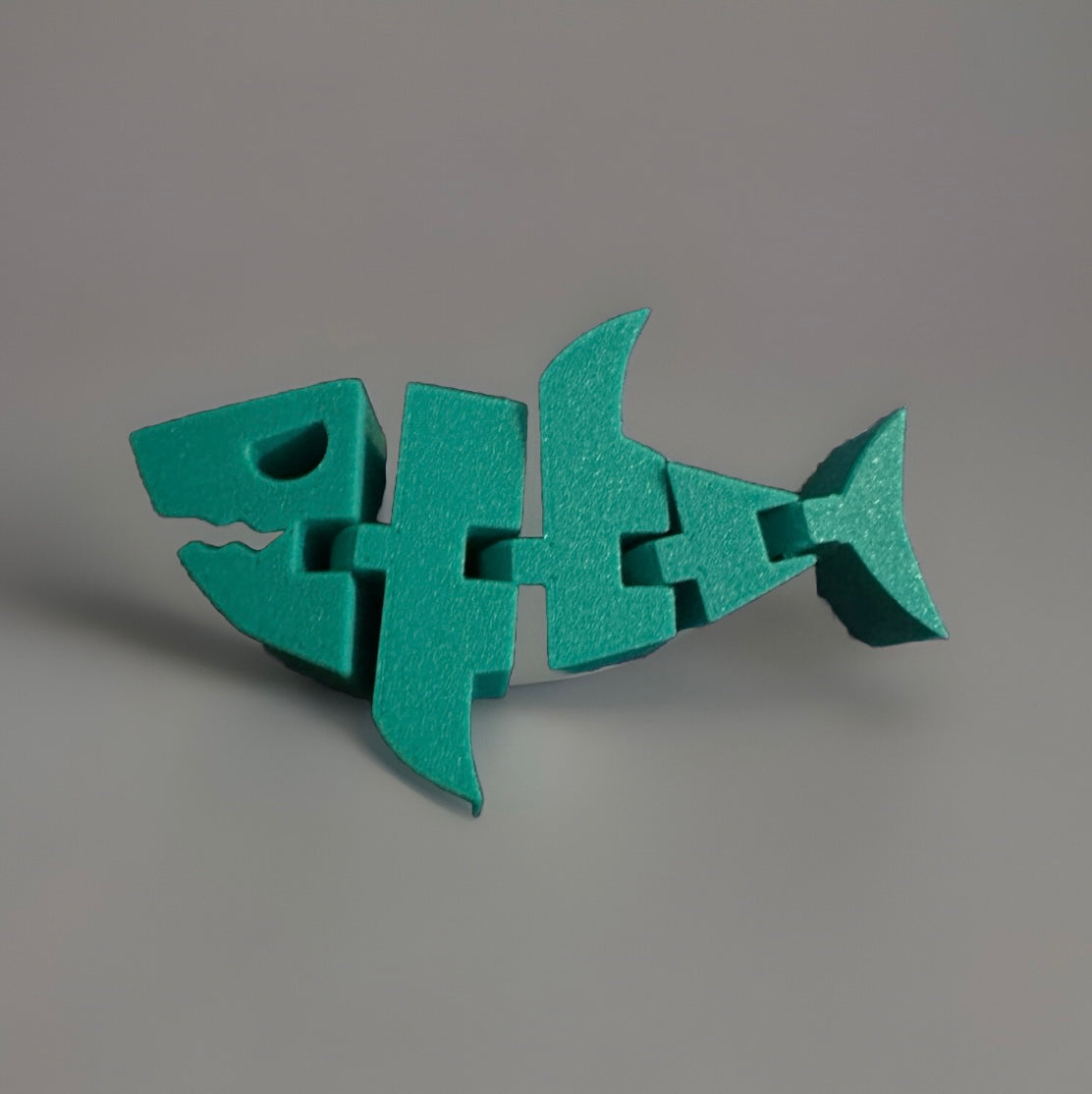 Green wooden articulated shark fidget toy with segmented movable parts on gray background
