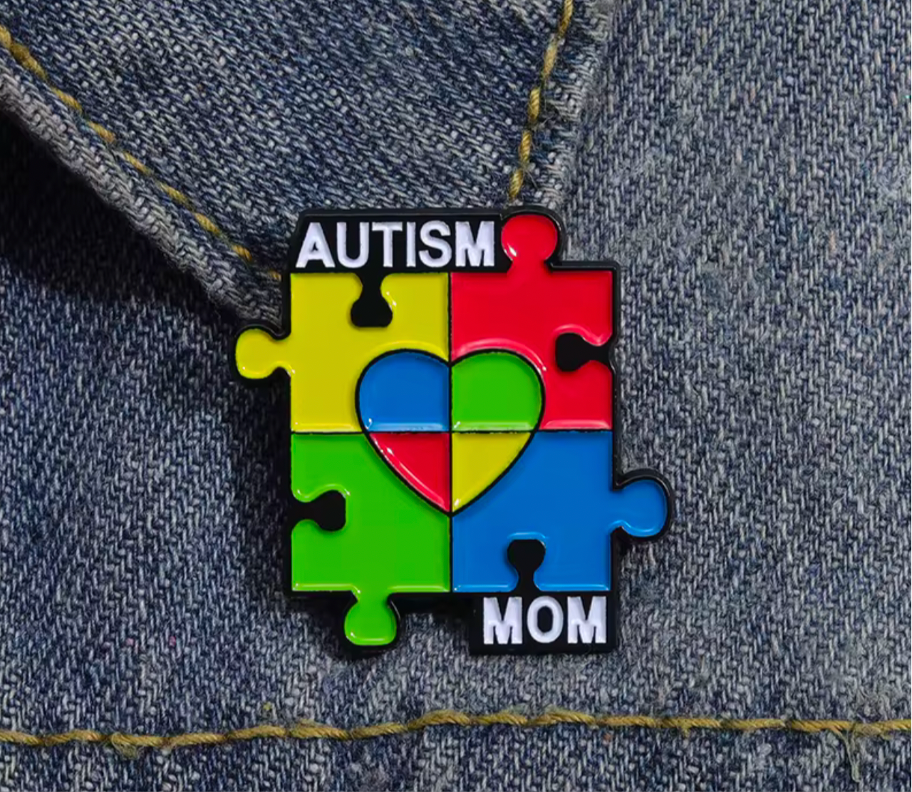 Autism awareness mom lapel pin with colorful puzzle pieces and heart design on denim fabric