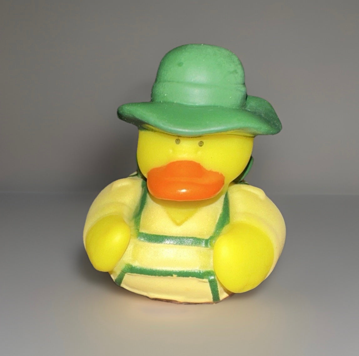 Camper rubber duck collectible wearing a green hat and yellow overalls from Reed’s Rubber Ducks and Sensory Shop