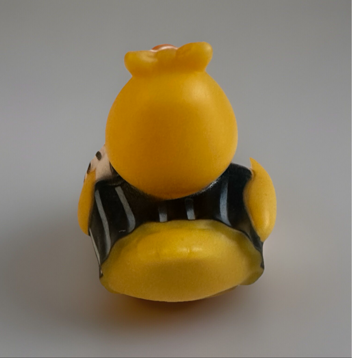 Back view of cheerleader rubber duck toy wearing black and white pom pom outfit
