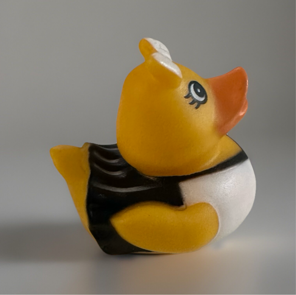 Cheerleader rubber duck toy in black and white outfit with orange beak and cute eye design