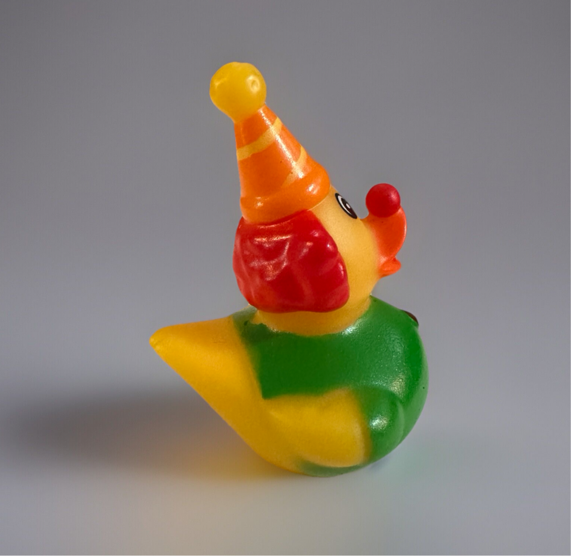 Colorful clown rubber duck wearing an orange party hat with red hair and green outfit