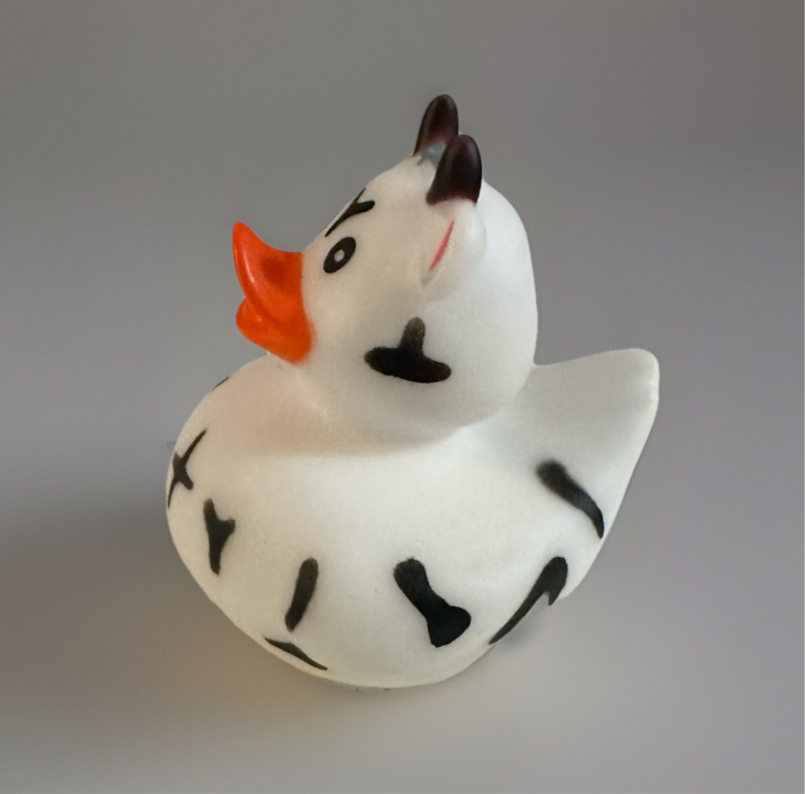 White cow rubber duck with black spots and orange beak from Reed’s Rubber Ducks and Sensory Shop