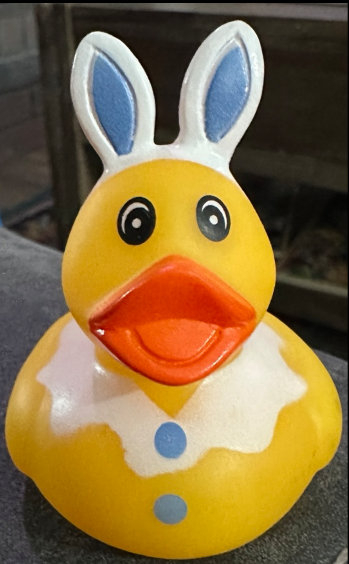 Yellow Easter bunny rubber duck with white and blue bunny ears and blue buttons on chest