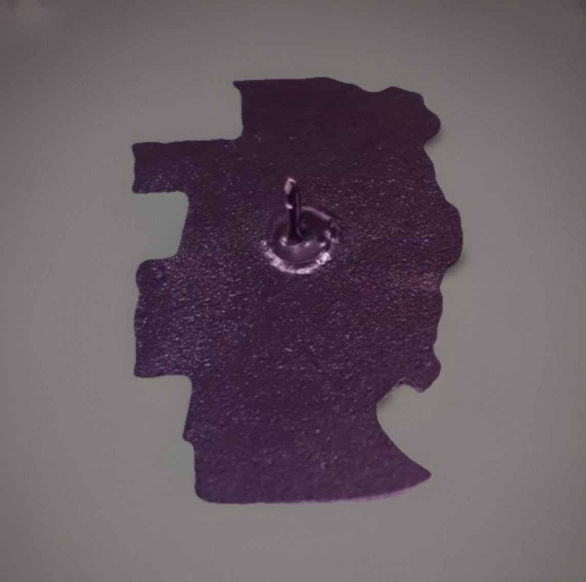 Back side view of a purple metal Frida inspired pin from Reed’s Rubber Ducks and Sensory Shop
