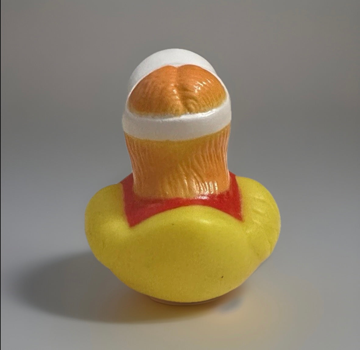 Rear view of lifeguard rubber duck with white cap and red and yellow lifeguard outfit