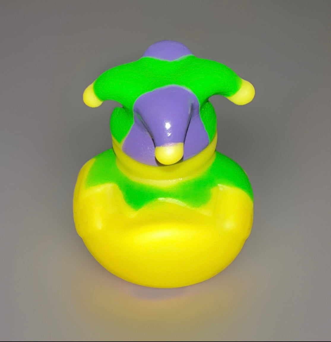 Yellow Mardi Gras rubber duck wearing a green and purple jester hat with yellow tips