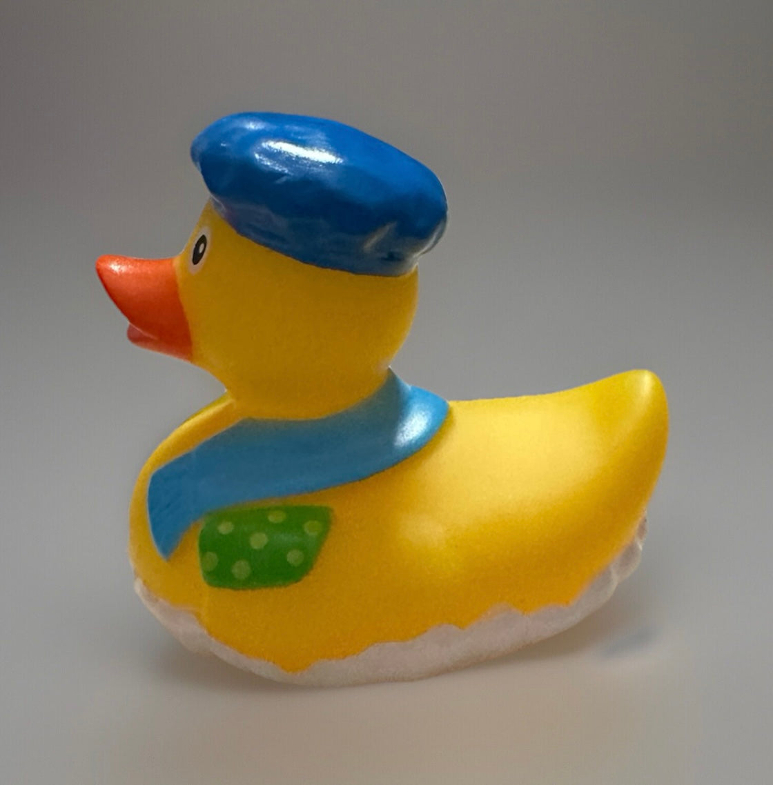 Yellow novelty rubber duck wearing a blue sailor hat and scarf with a green polka dot patch
