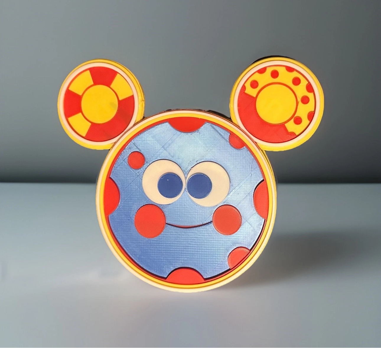 Oh Toodles figure gift with smiling blue face and colorful red and yellow ears from Reed’s Rubber Ducks and Sensory Shop