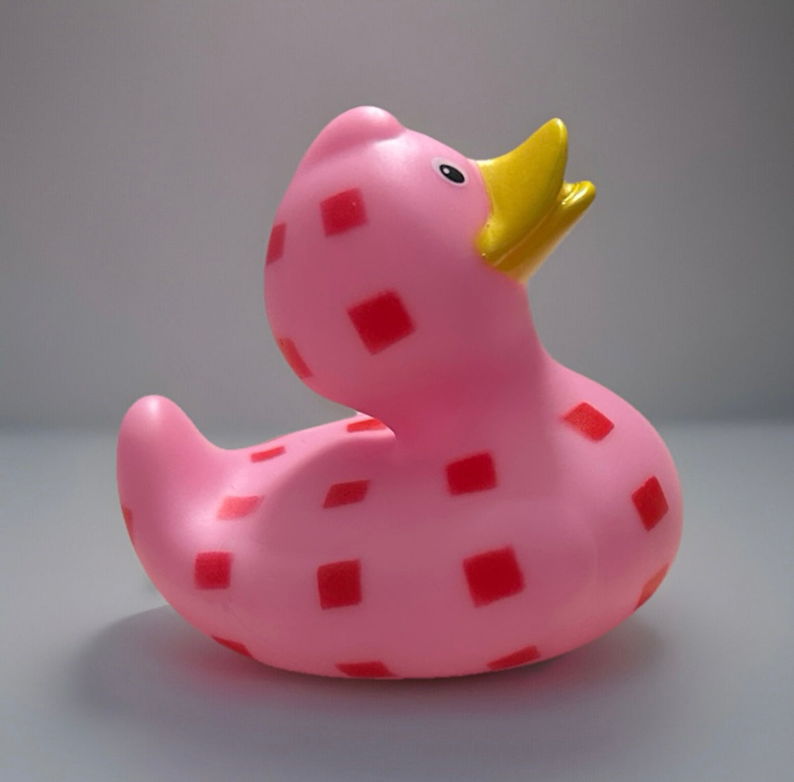 Pink checkered rubber duck with red squares and yellow beak from Reeds Rubber Ducks and Sensory Shop
