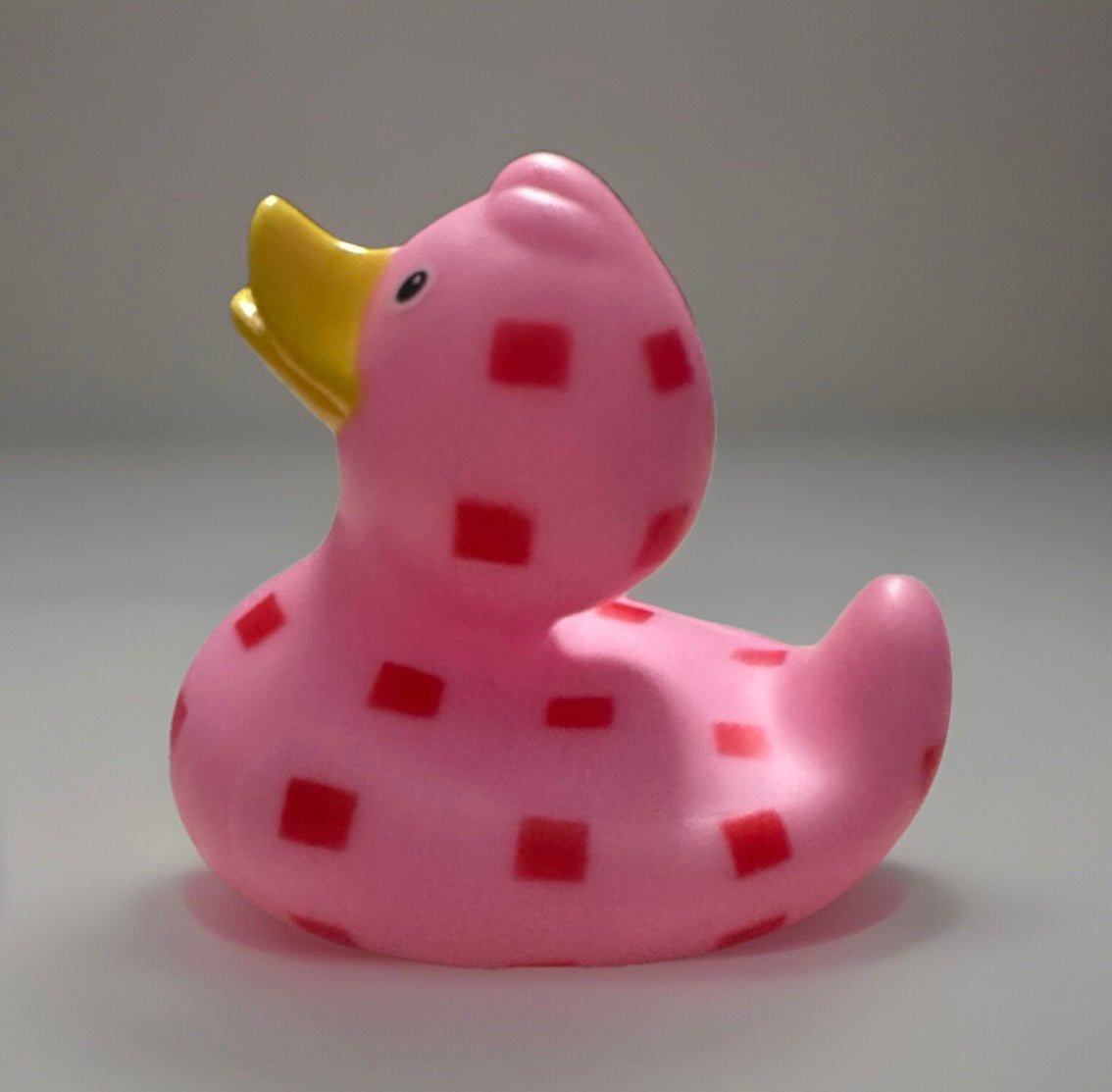 Pink checkered rubber duck with red squares and a yellow beak from Reed’s Rubber Ducks and Sensory Shop