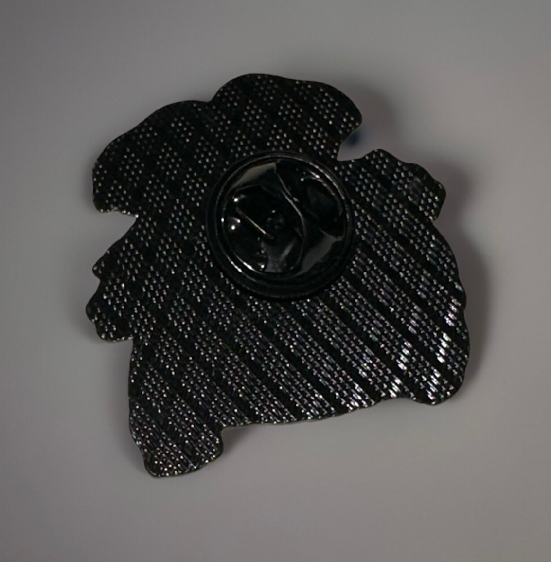 Back view of a Pokemon Venusaur enamel pin showing the black metal pin clasp and textured backing