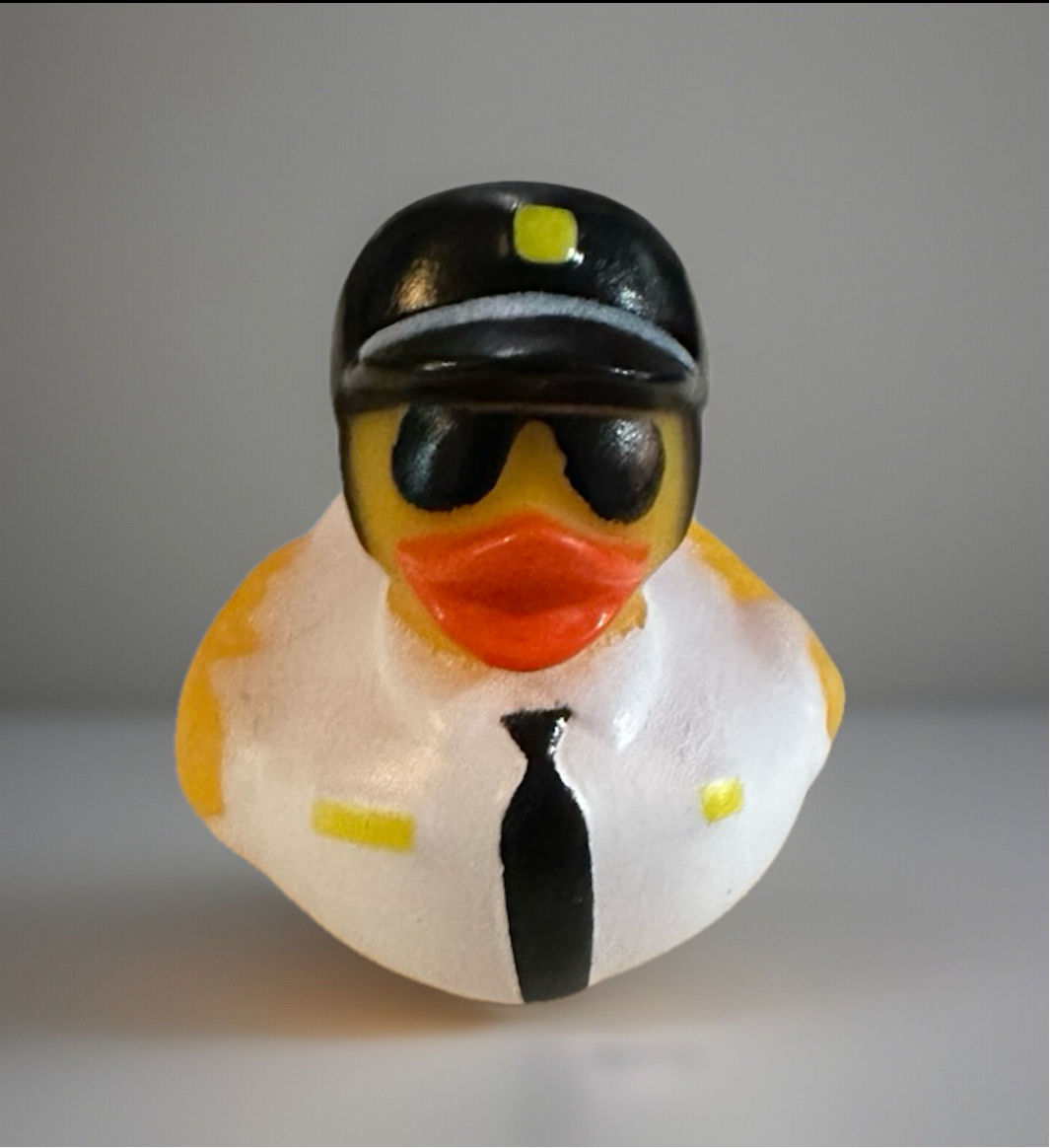 Police rubber duck wearing black police hat, sunglasses, white shirt, and black tie from Reed’s Rubber Ducks and Sensory Shop