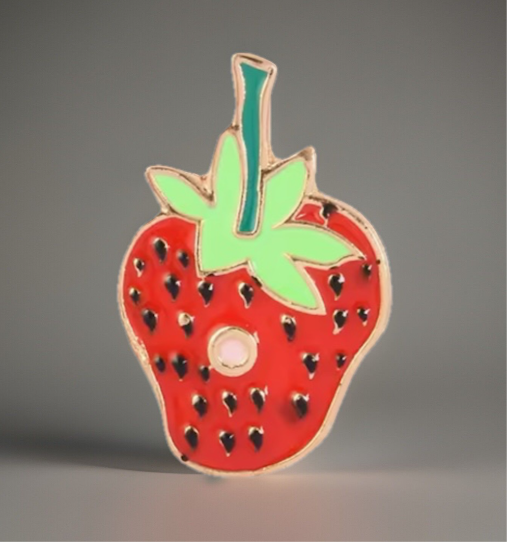 Red strawberry enamel pin with green leaves on a gray background from Reed’s Rubber Ducks and Sensory Shop caterpillar enamel pins