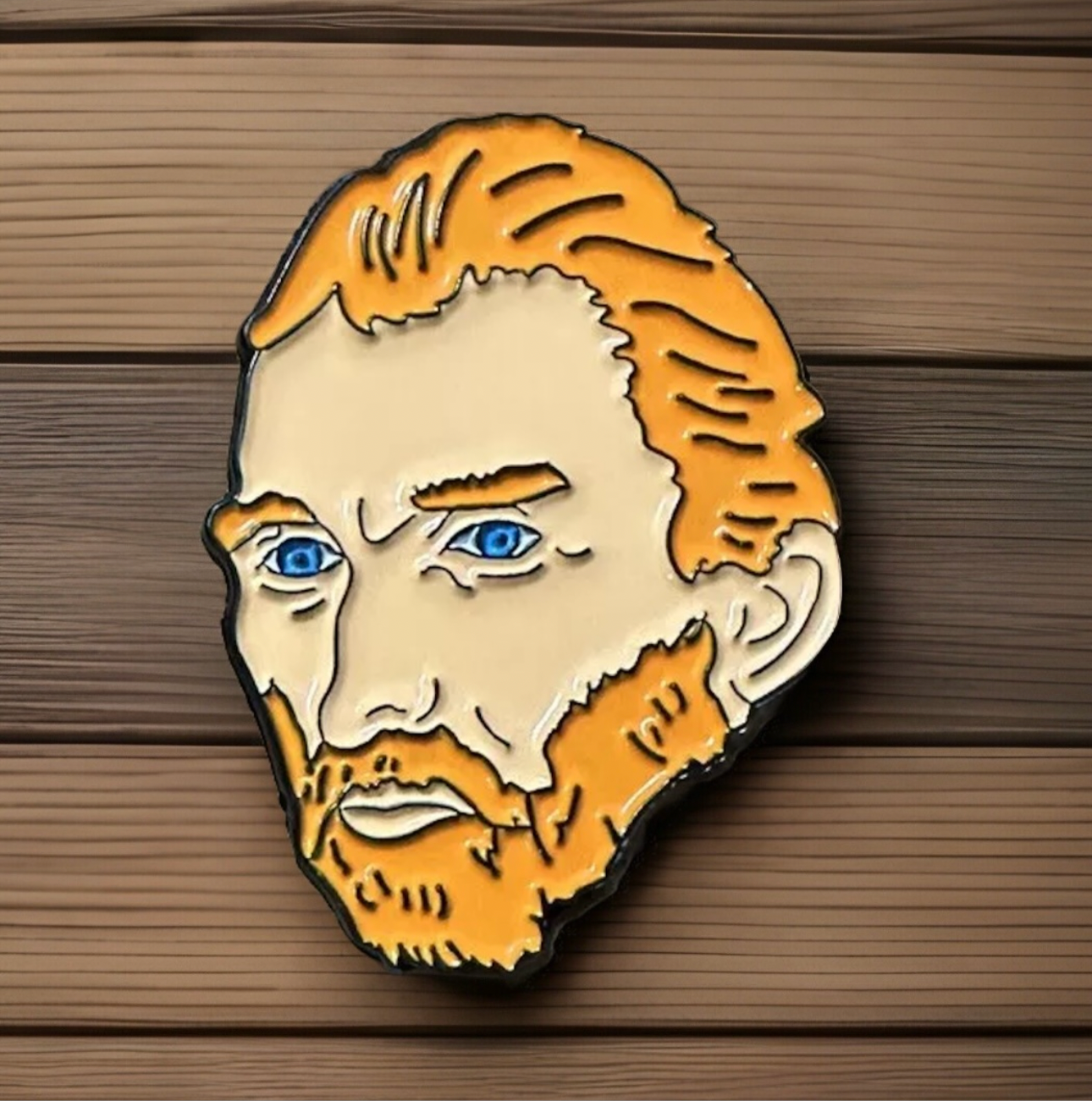 Van Gogh enamel pin featuring detailed orange hair and blue eyes on a wooden background