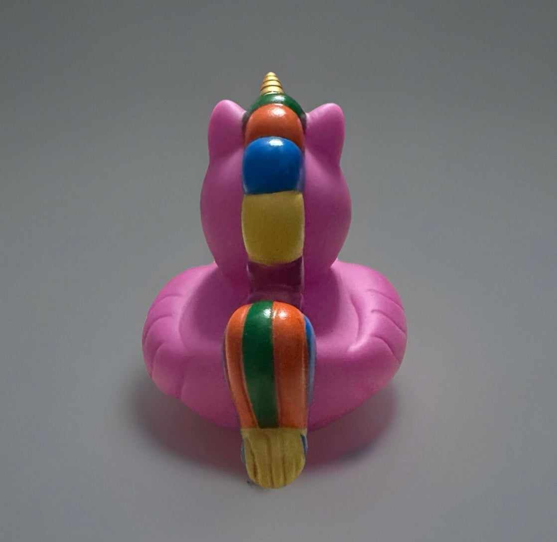 Pink unicorn rubber duck with colorful mane and golden horn viewed from the back