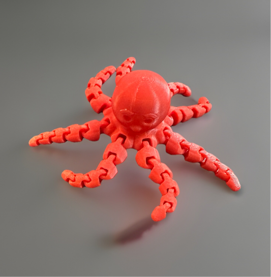 Red 3D articulated fidget octopus toy with flexible jointed tentacles on a gray surface