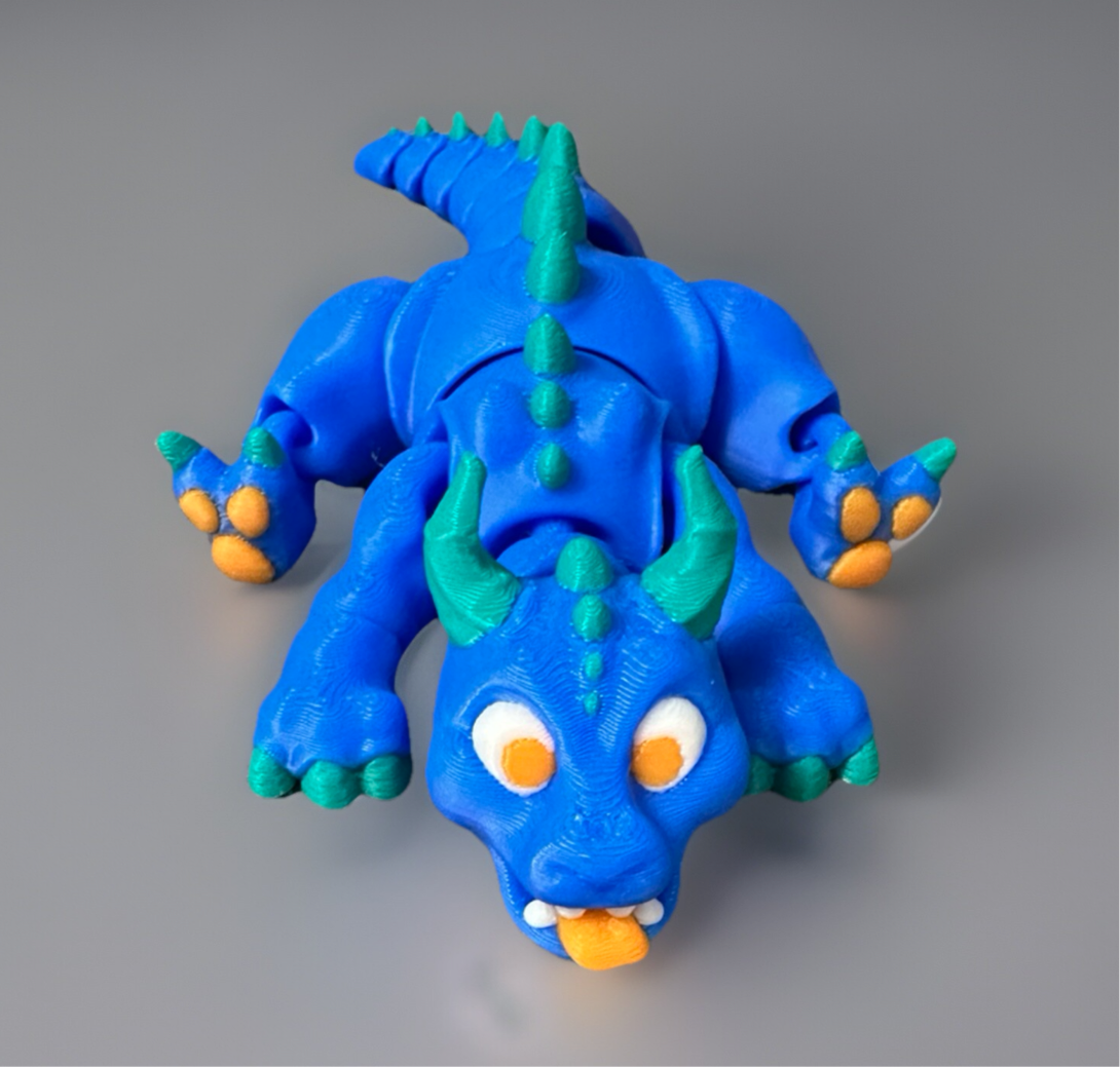 Blue and green 3D fidget dragon toy with orange eyes and claws for sensory play