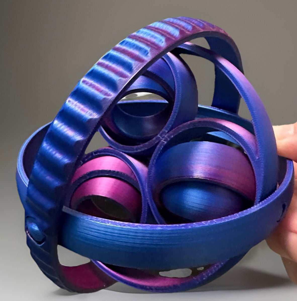Colorful 3D fidget rings for sensory relief in blue and purple held in hand