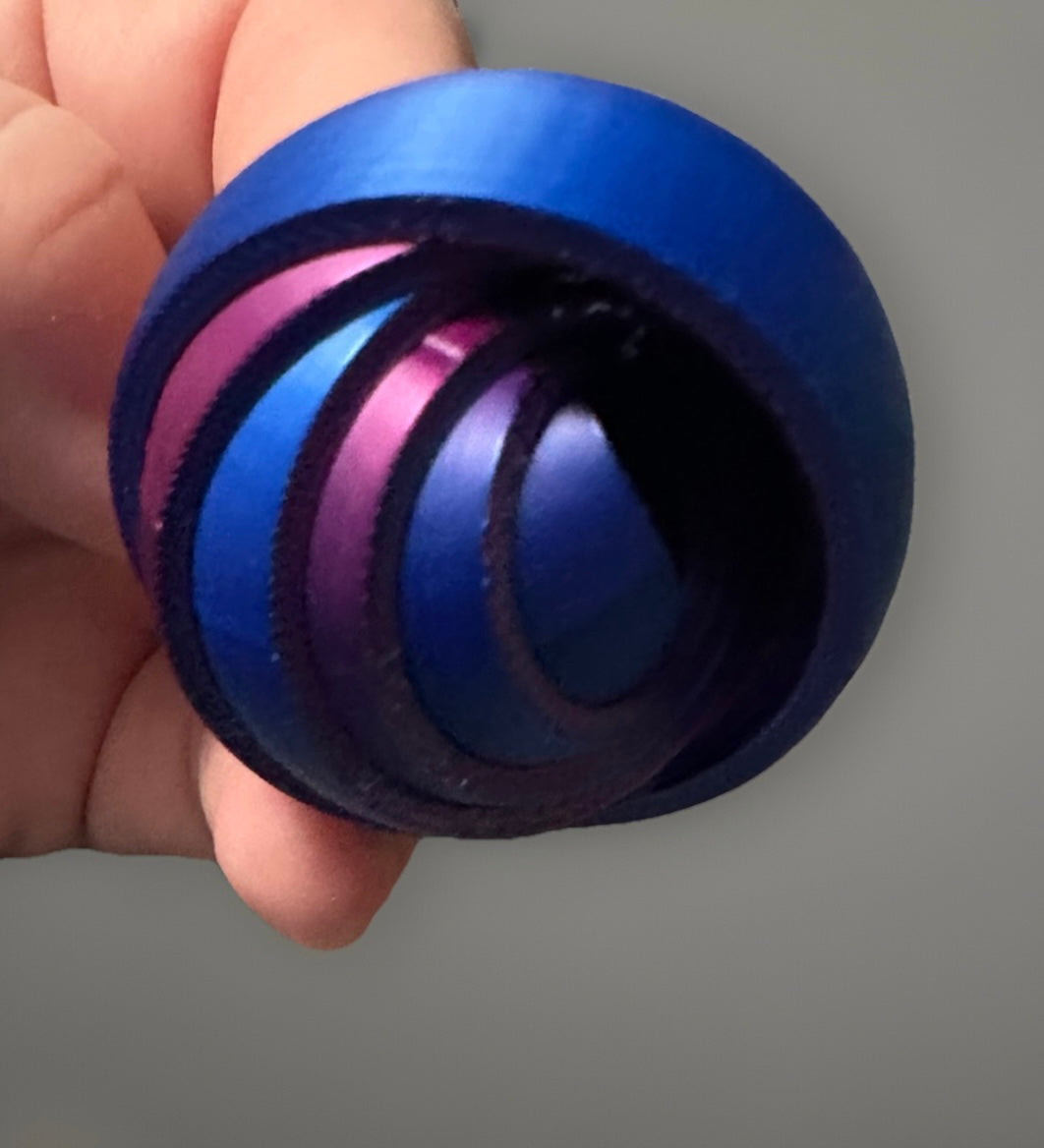 Blue and purple metal 3D gyro finger fidget spinner held between fingers