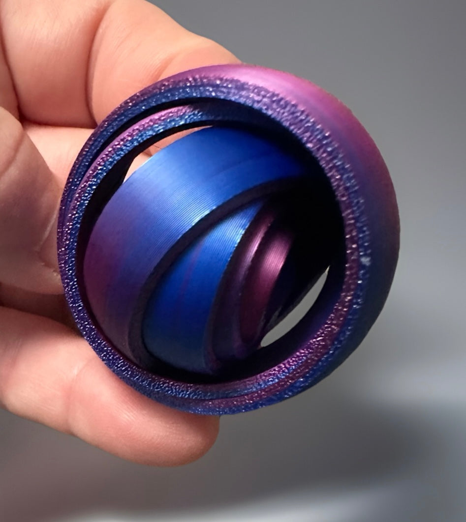 Blue and purple metallic 3D gyro finger fidget spinner held in hand with textured rings