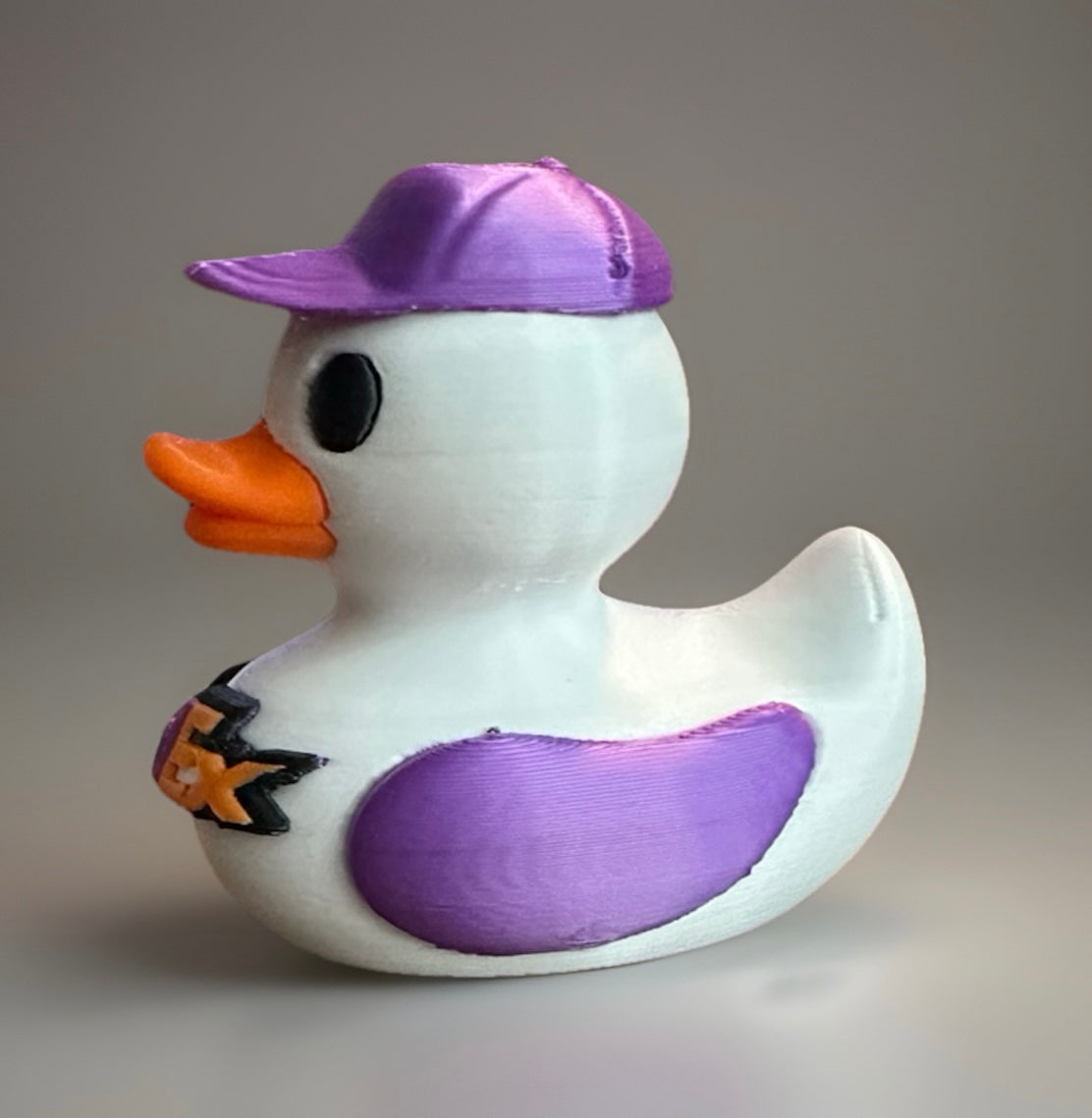3D printed FedEx duck with purple cap and wing details, featuring an orange beak and FedEx logo on the chest