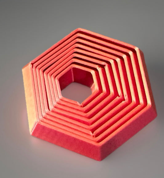 Red 3D printed fidget toy hexagon with layered geometric design for sensory play
