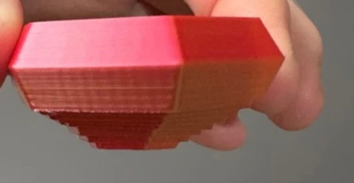 Hand holding a red 3D printed fidget toy hexagon with textured layers for sensory play