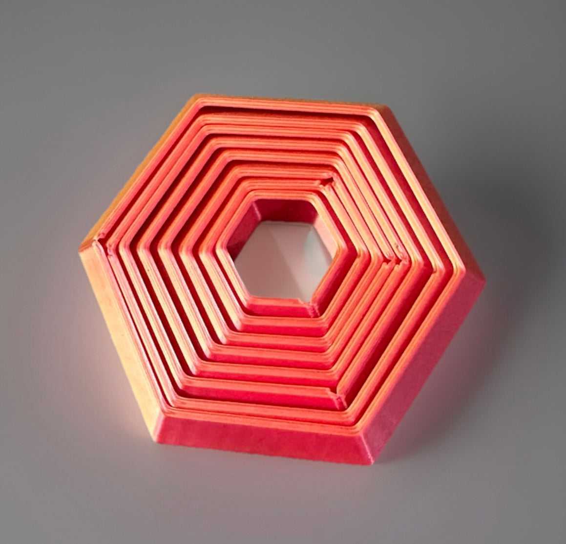 Red 3D printed fidget toy hexagon with nested concentric layers for sensory play