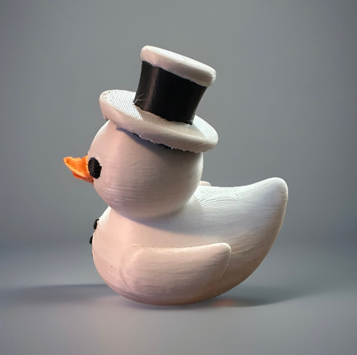 3D printed snowman duck wearing a black top hat with an orange beak from Reed’s Rubber Ducks and Sensory Shop