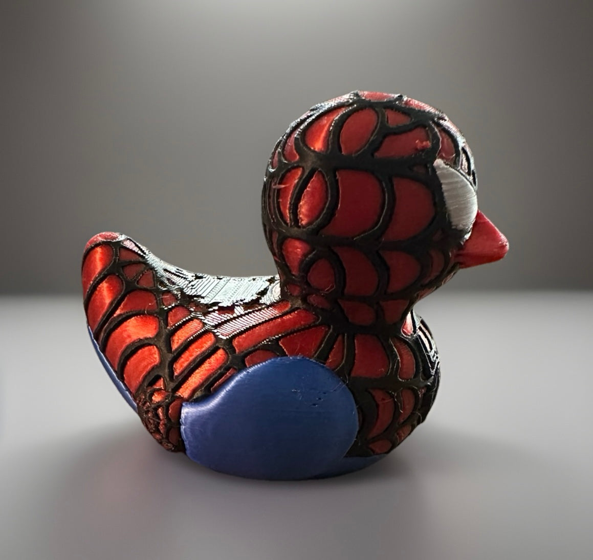 3D printed Spider-Man duck figurine with red and black web pattern and blue wings