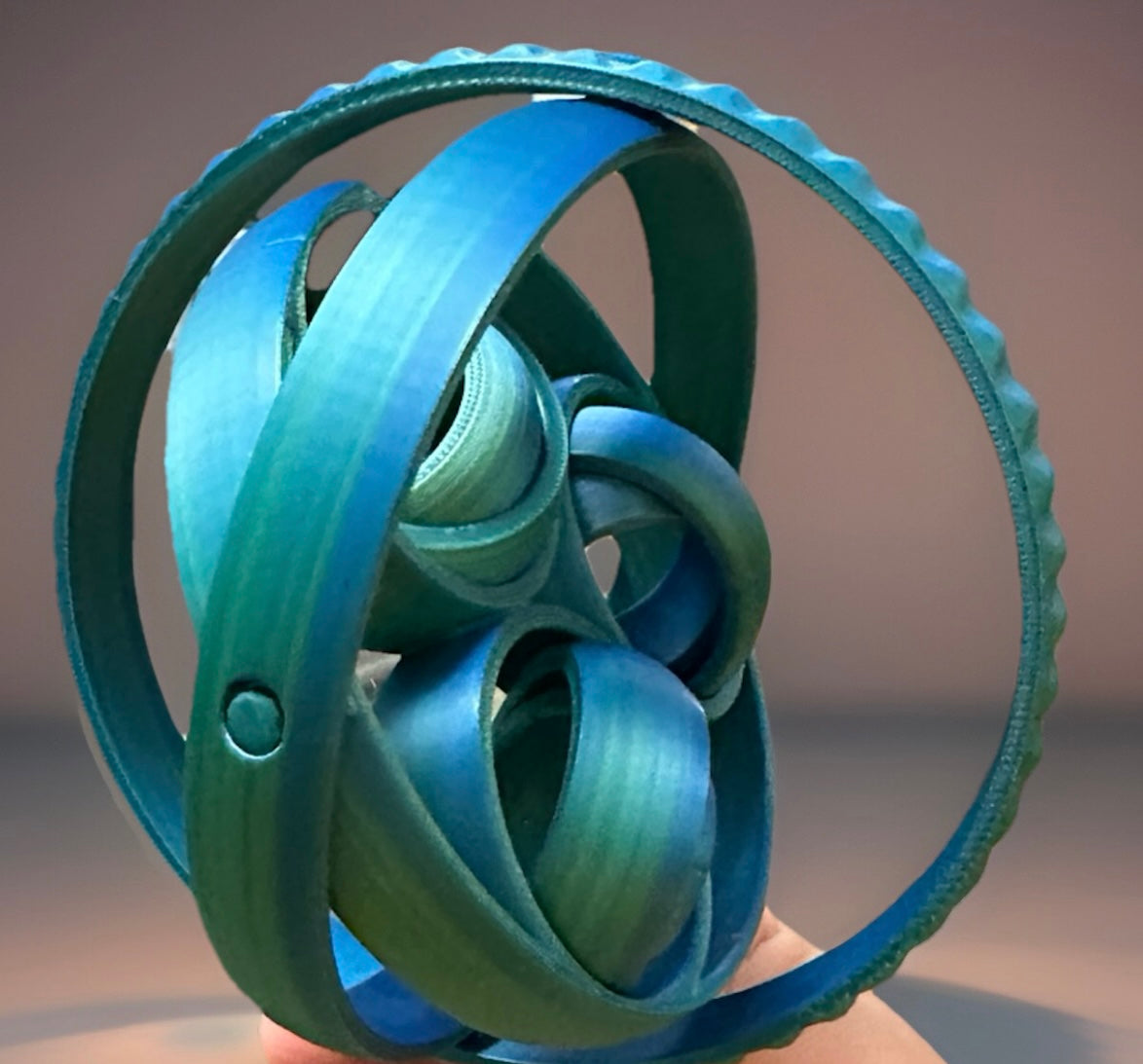 Blue 3D rotating fidget rings held in hand with interlocking circular design for stress relief