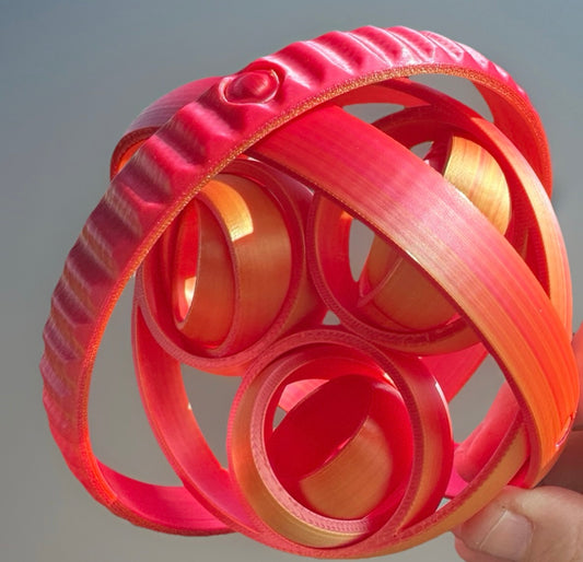 Red 3D rotating fidget rings held by hand from Reeds Rubber Ducks and Sensory Shop
