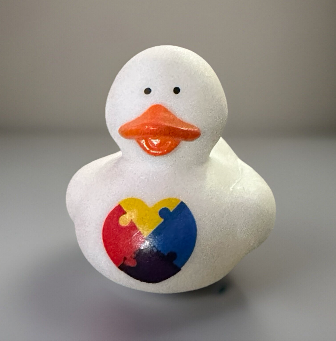 White Autism awareness rubber duck with puzzle piece heart design from Reed’s Rubber Ducks and Sensory Shop