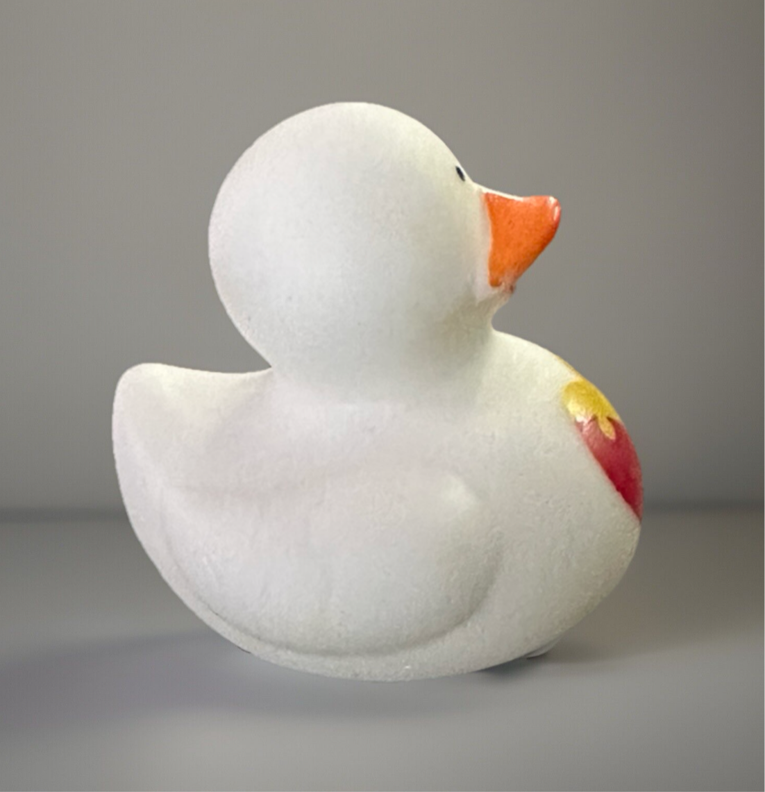 White Autism awareness rubber duck with orange beak and colorful puzzle heart on side
