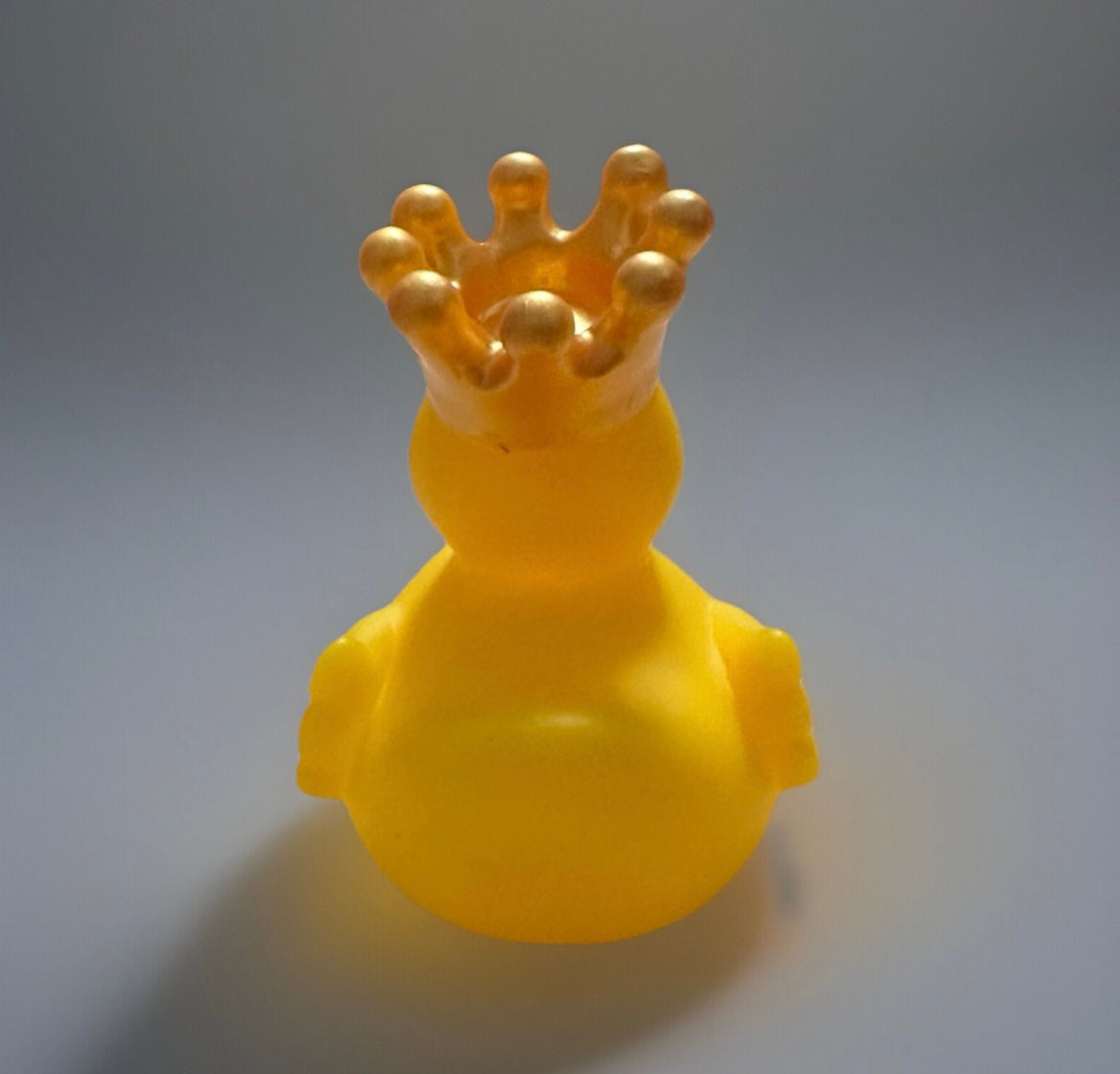 Yellow crowned rubber duck gift with a shiny golden crown on a gray background