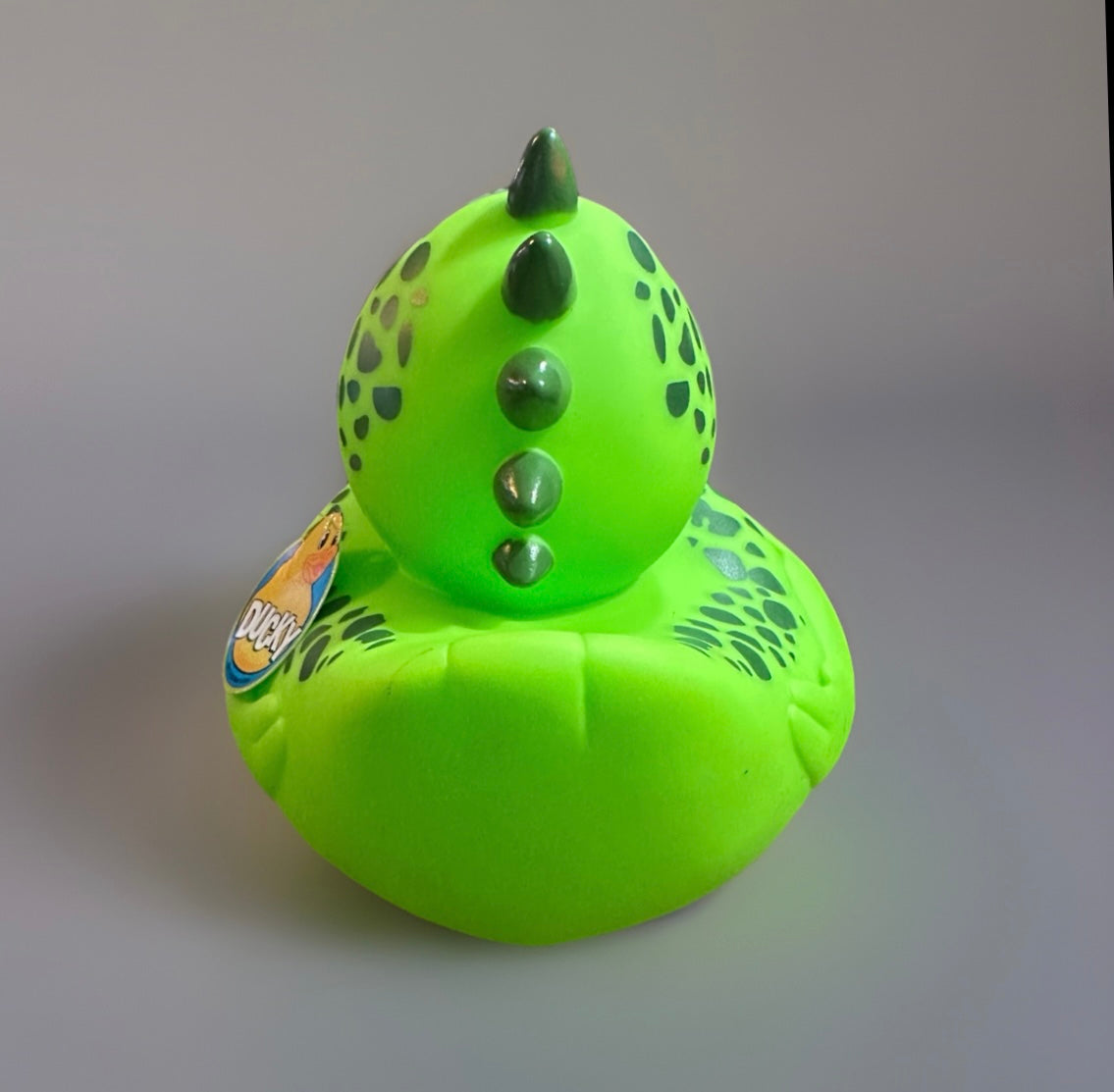 Bright green dinosaur rubber duck with black spots and spikes on back from Reed’s Rubber Ducks and Sensory Shop