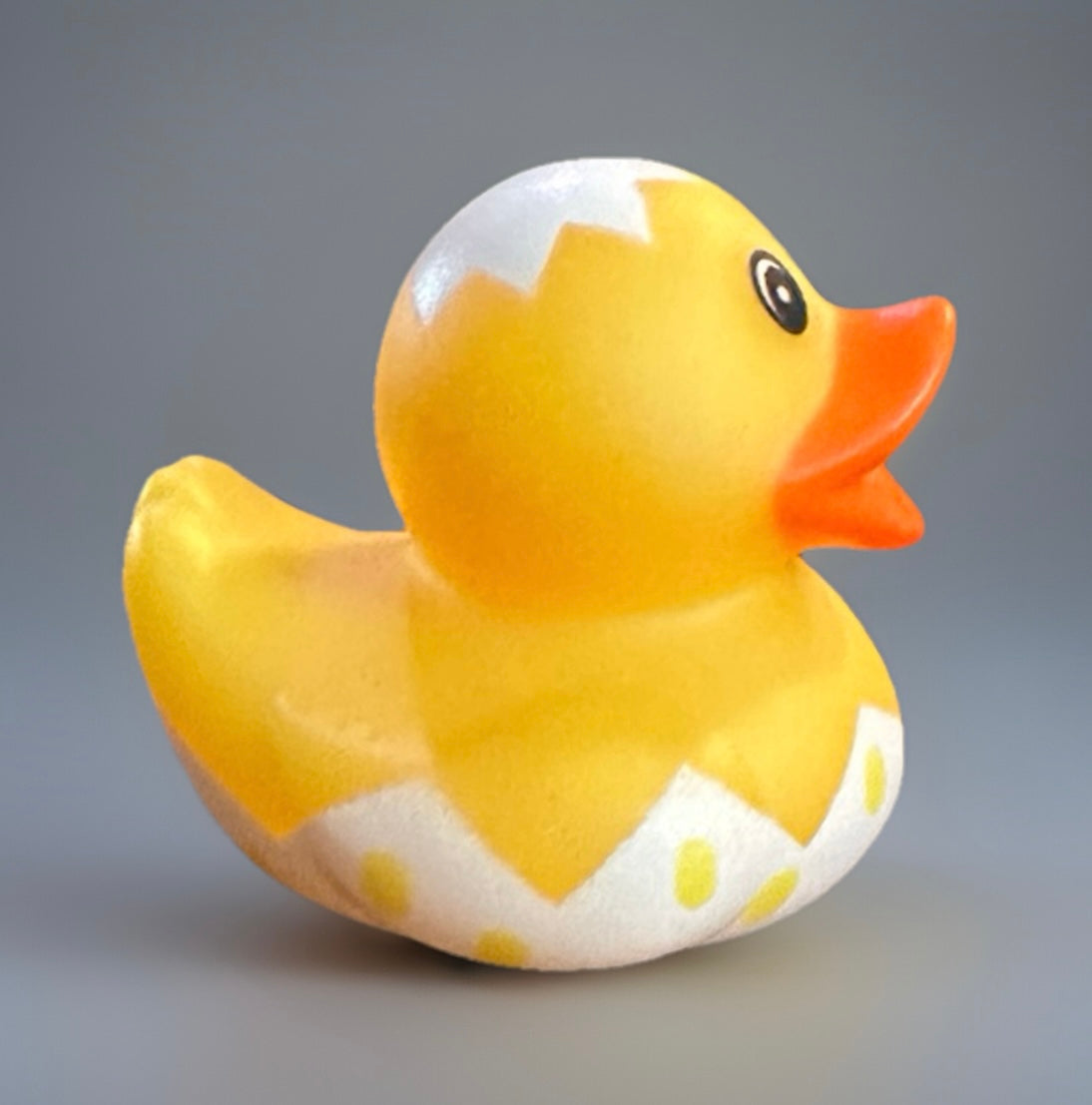 Yellow Easter egg rubber duck with white cracked egg design and orange beak on gray background