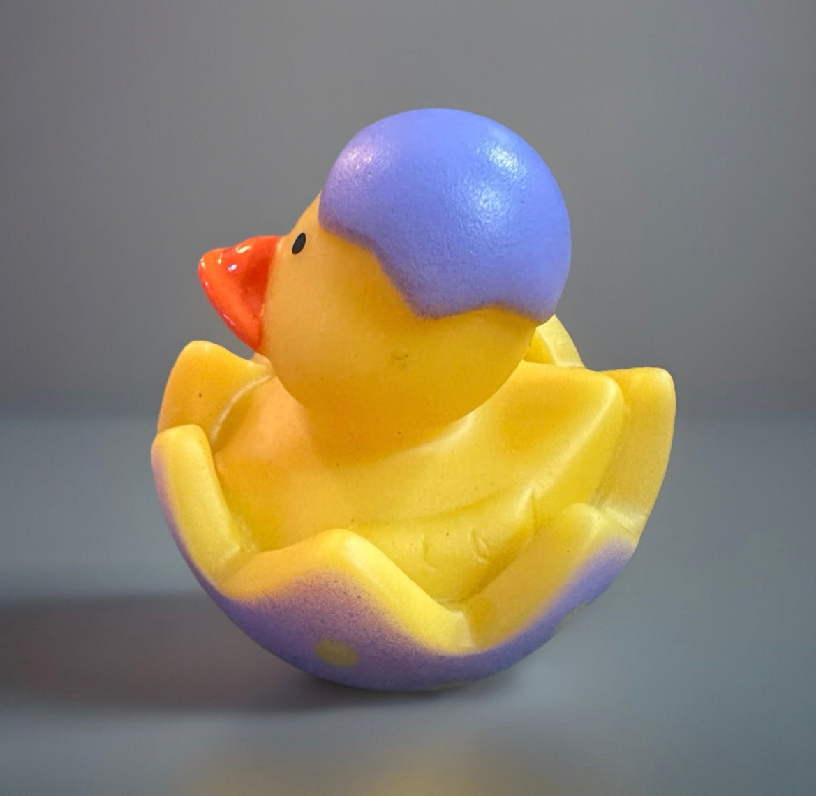 Yellow rubber duck with purple top sitting inside pastel purple cracked egg Easter rubber duck gift