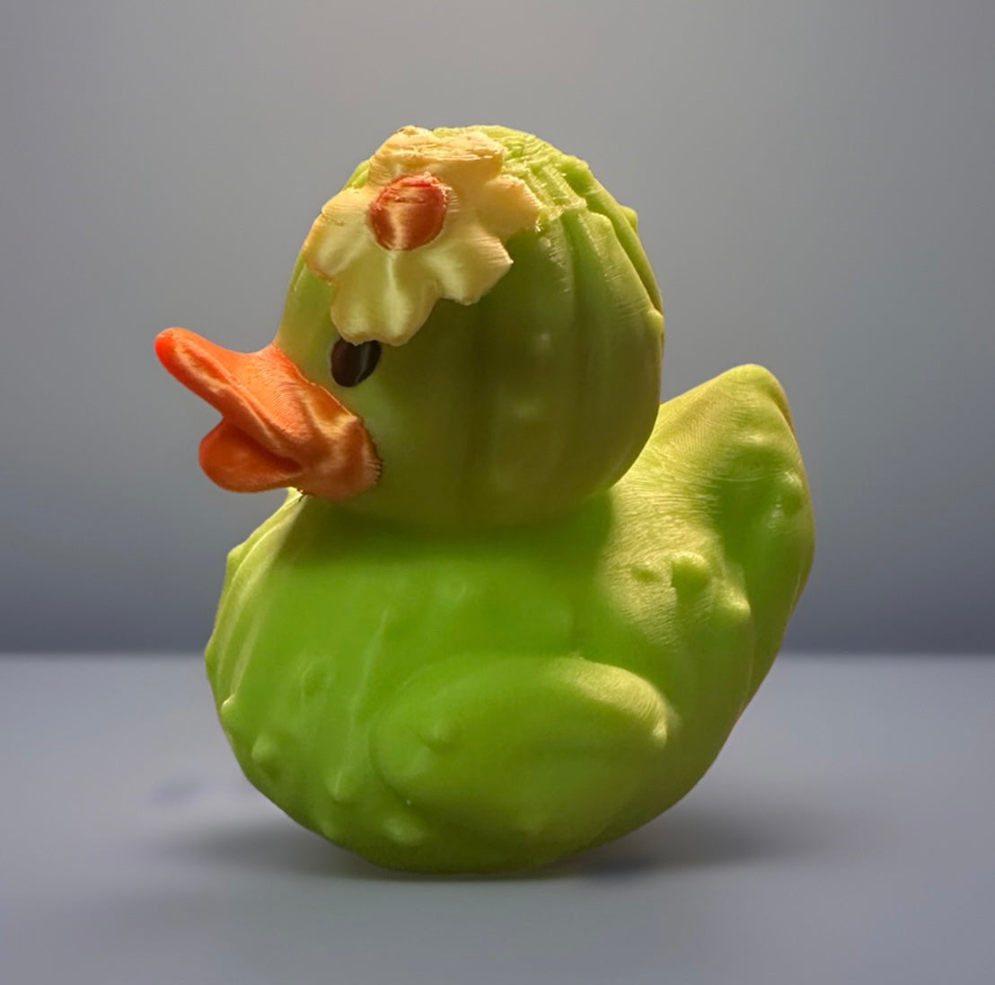 Green 3D printed cactus duck with orange beak and yellow flower designed by Reed’s Rubber Ducks and Sensory Shop
