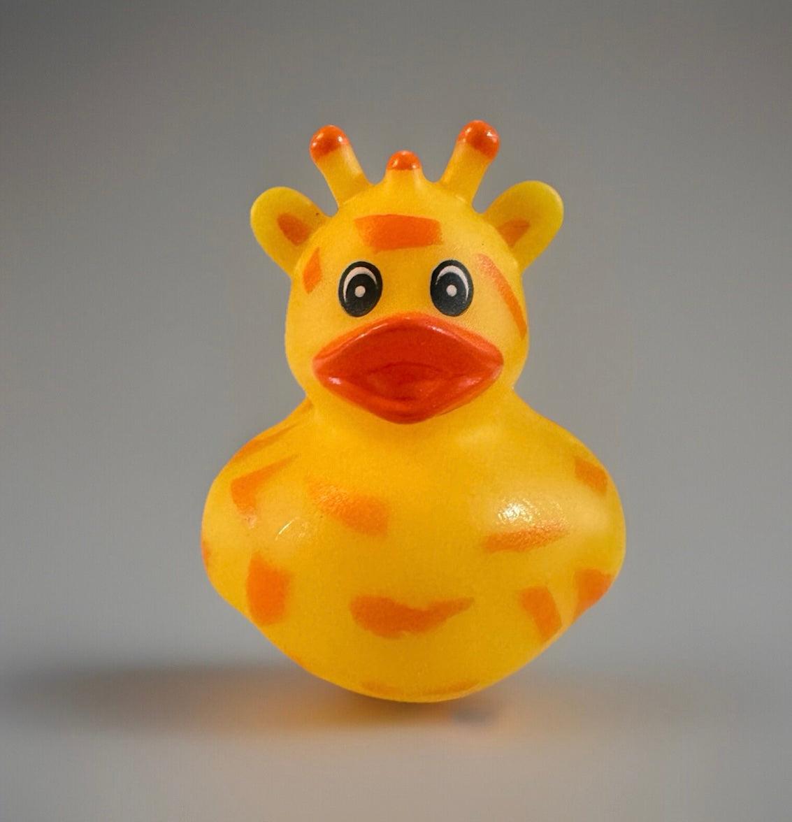 Bright yellow giraffe rubber duck toy with orange spots and cartoon eyes from Reed’s Rubber Ducks and Sensory Shop