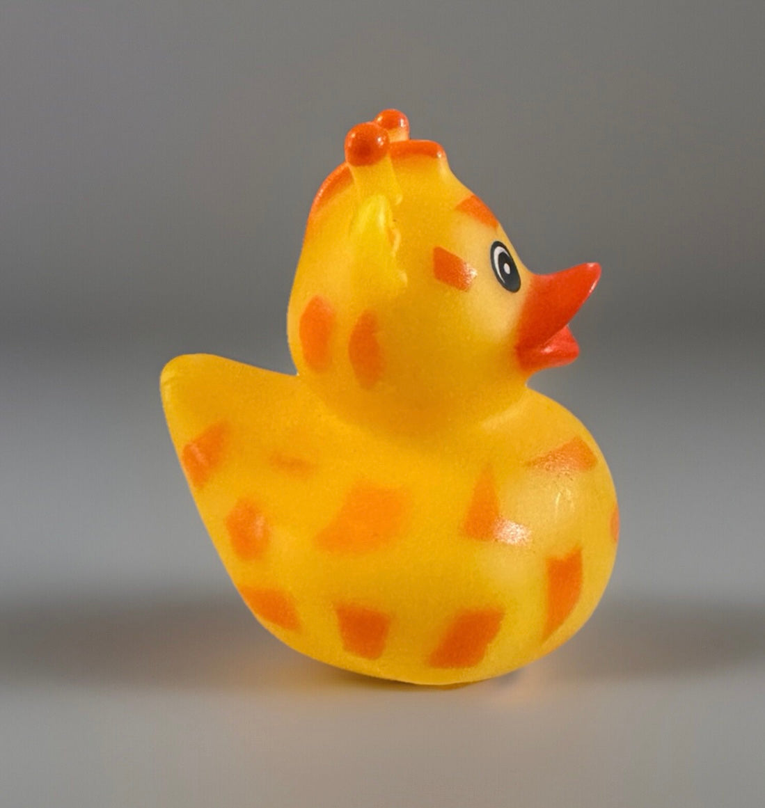 Yellow giraffe rubber duck toy with orange spots and a bright orange beak from Reed’s Rubber Ducks and Sensory Shop