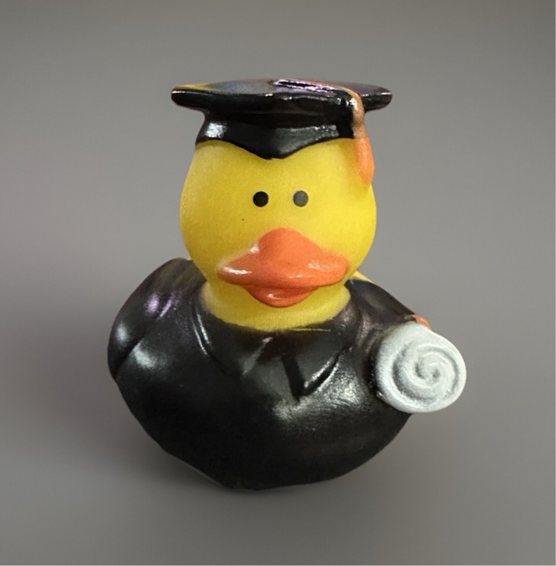 Graduation rubber duck gift wearing a black cap and gown holding a diploma scroll