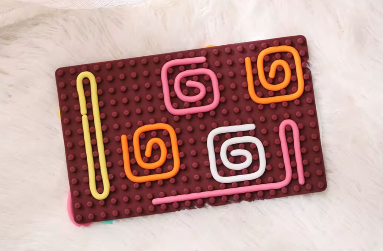 Maroon sensory activity mat with colorful raised spiral and line patterns for tactile play