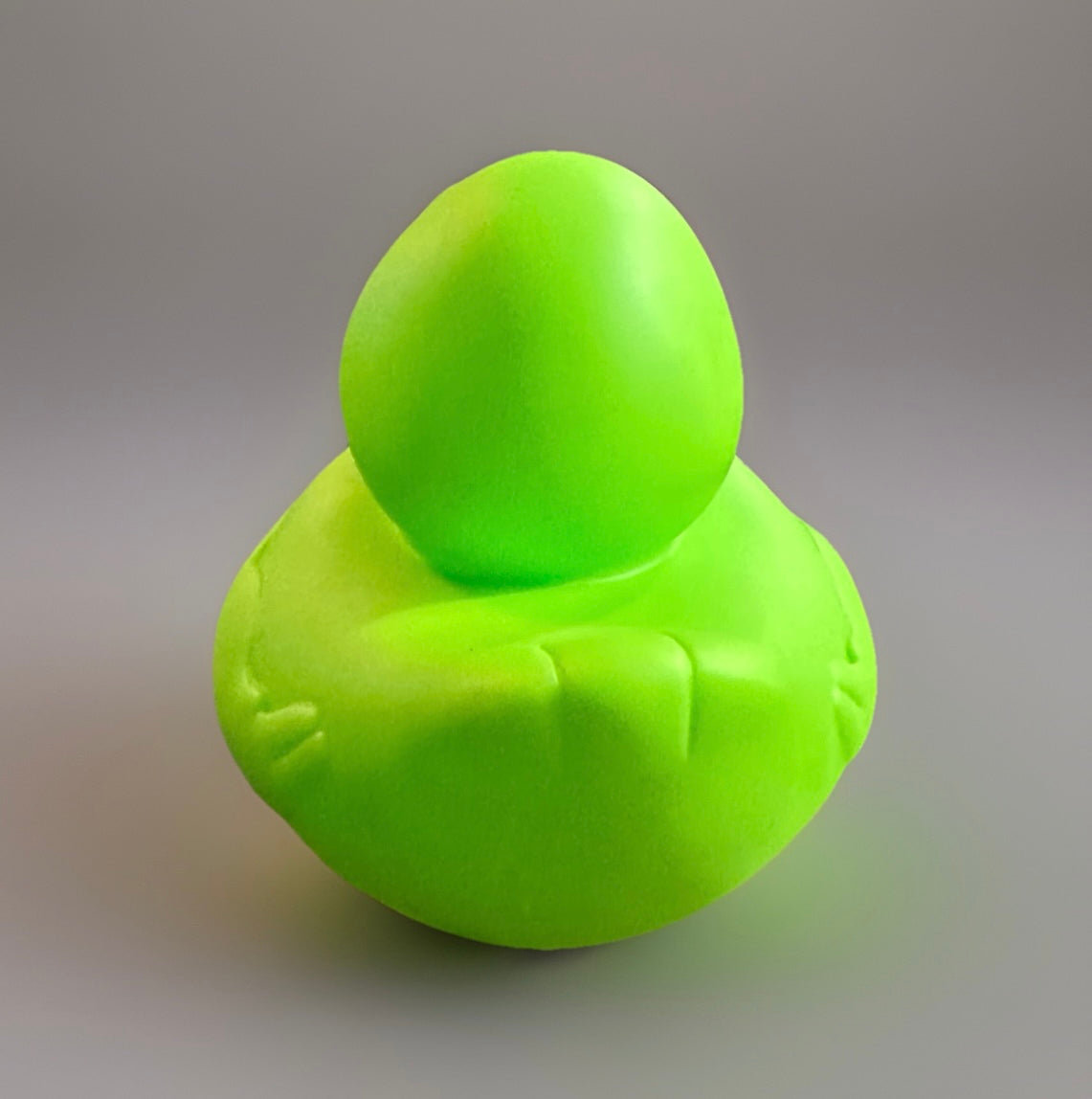 Neon green alien rubber duck with smooth surface and simple alien features