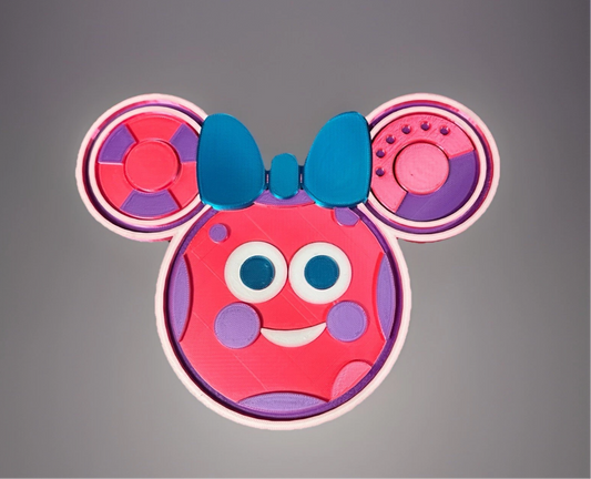 Colorful Oh Quoodles figure with blue bow and playful facial features in pink and purple tones