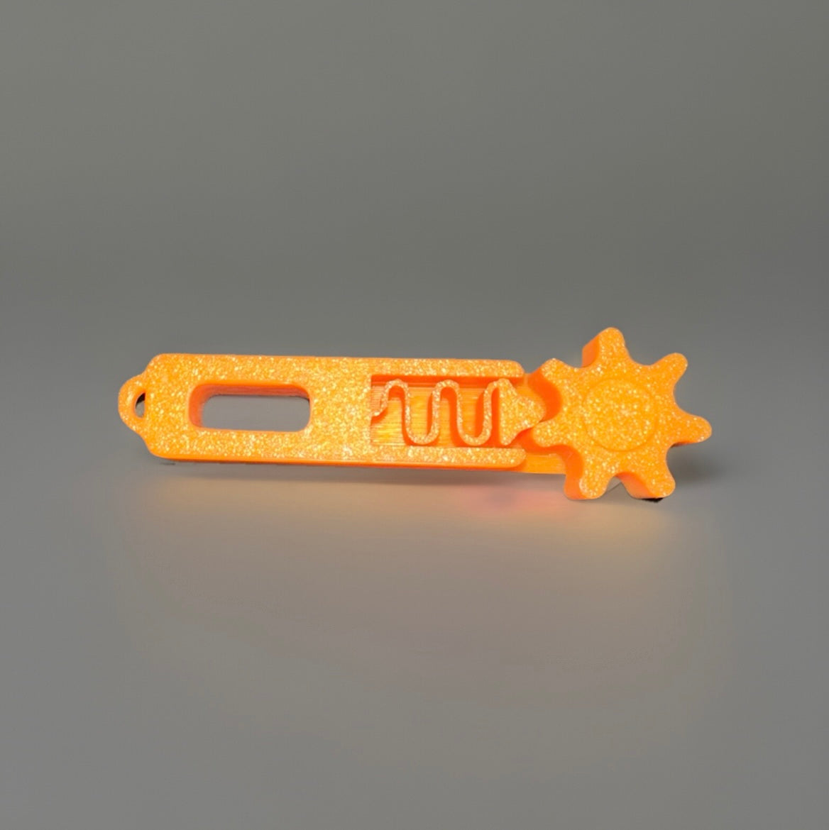 Orange 3D printed fidget keychain with a gear-shaped spinner and textured body